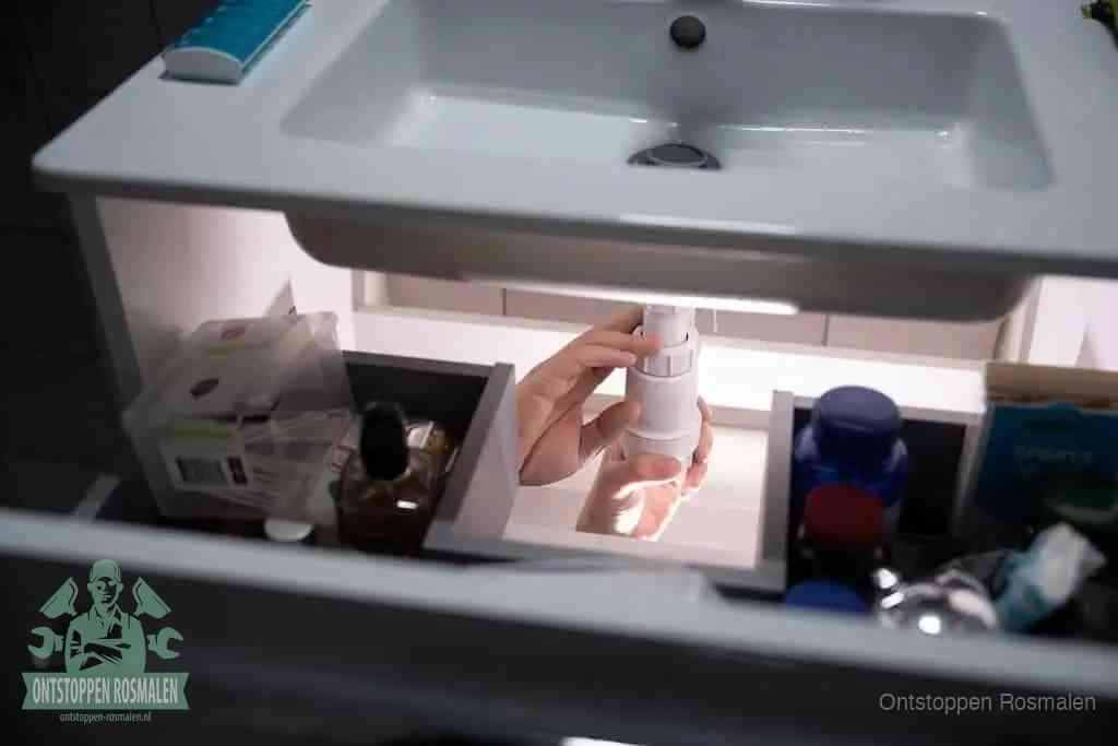 Een pompfles met zeep boven een wastafel, de heet water en afwasmiddel-methode om een vetprop in de afvoer los te maken in Rosmalen