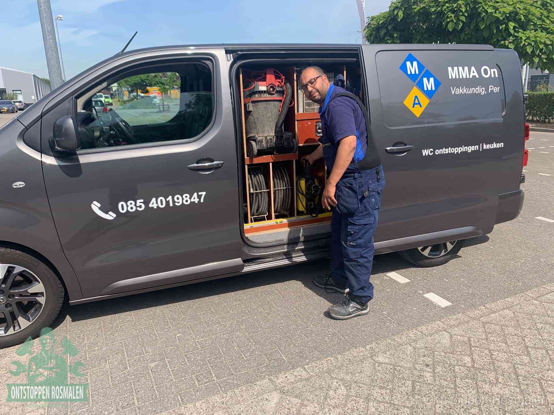 Een monteur bij de open schuifdeur van zijn bedrijfsbus op een parkeerplaats, klaar om de oorzaak van terugkerende afvoerverstoppingen aan te pakken in Rosmalen