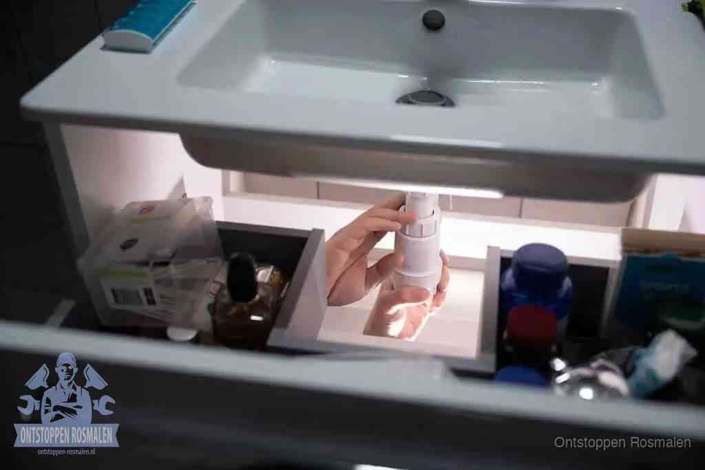 Een pompfles met zeep boven een wastafel in de toiletruimte, de warm water en afwasmiddel-methode om de wc te ontstoppen in Rosmalen