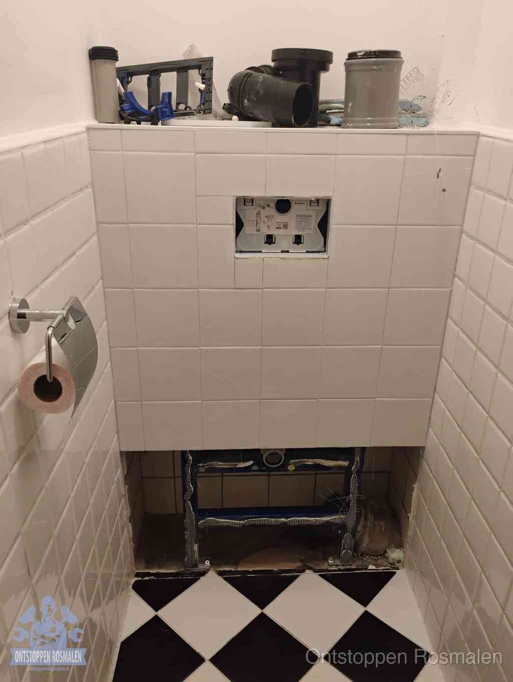 Een toiletruimte waar het hangtoilet en de inbouwreservoir-onderdelen zijn vrijgelegd voor onderhoud, periodiek nazicht voorkomt een wc-verstopping in Rosmalen