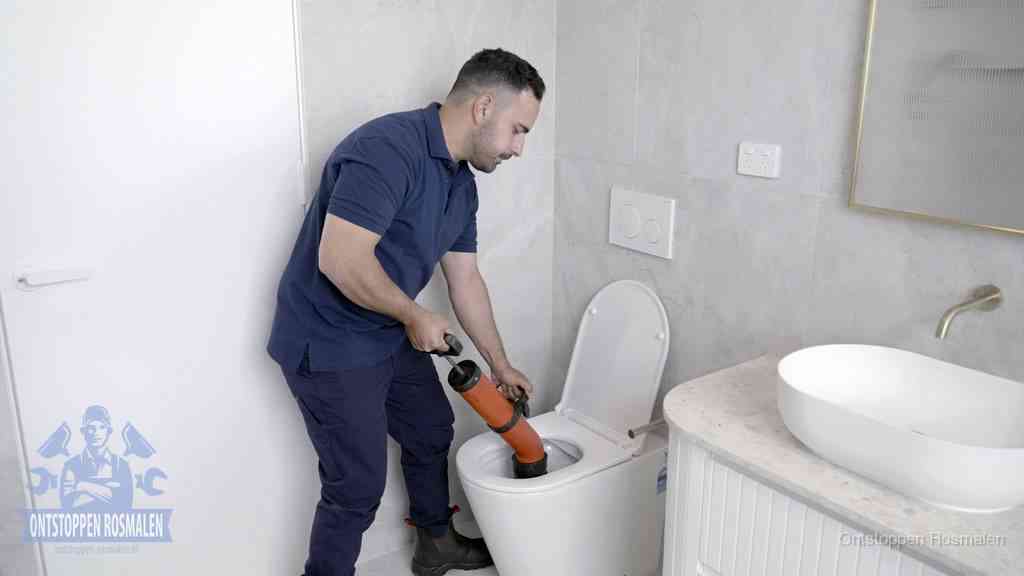 Een monteur gebruikt een handmatige perspomp (toiletontstopper) op een wandcloset tijdens het professioneel wc ontstoppen in Rosmalen