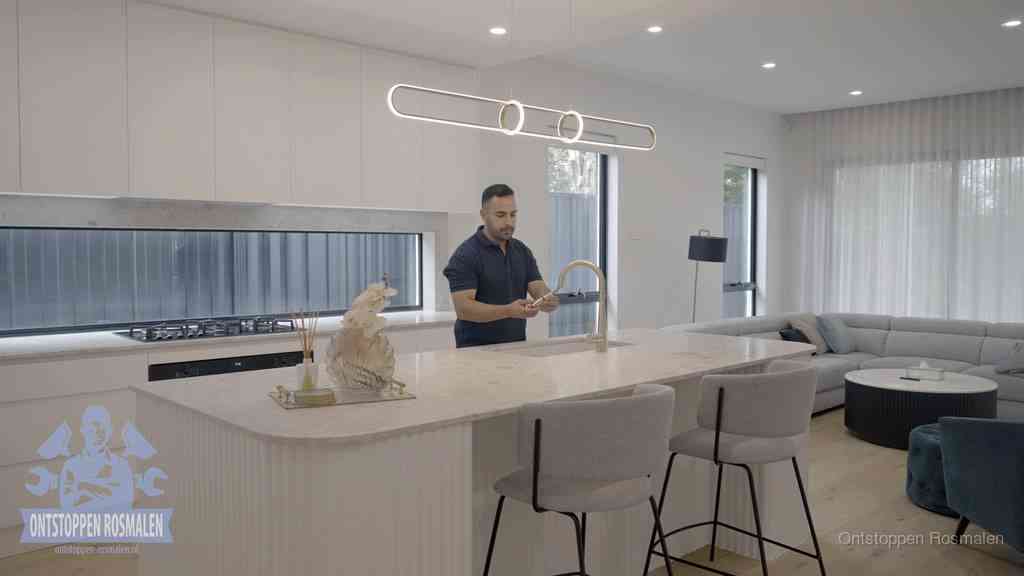 Een bewoner bij de keukenspoelbak die zelf aan de slag gaat met een verstopte gootsteen in Rosmalen